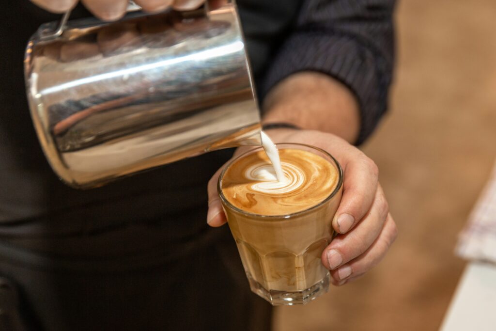 Versement du lait mousseux dans un espresso pour créer du latte art dans un café