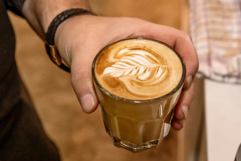 Verre de café avec latte art en forme de feuille, illustrant l'appréciation sensorielle du café de spécialité