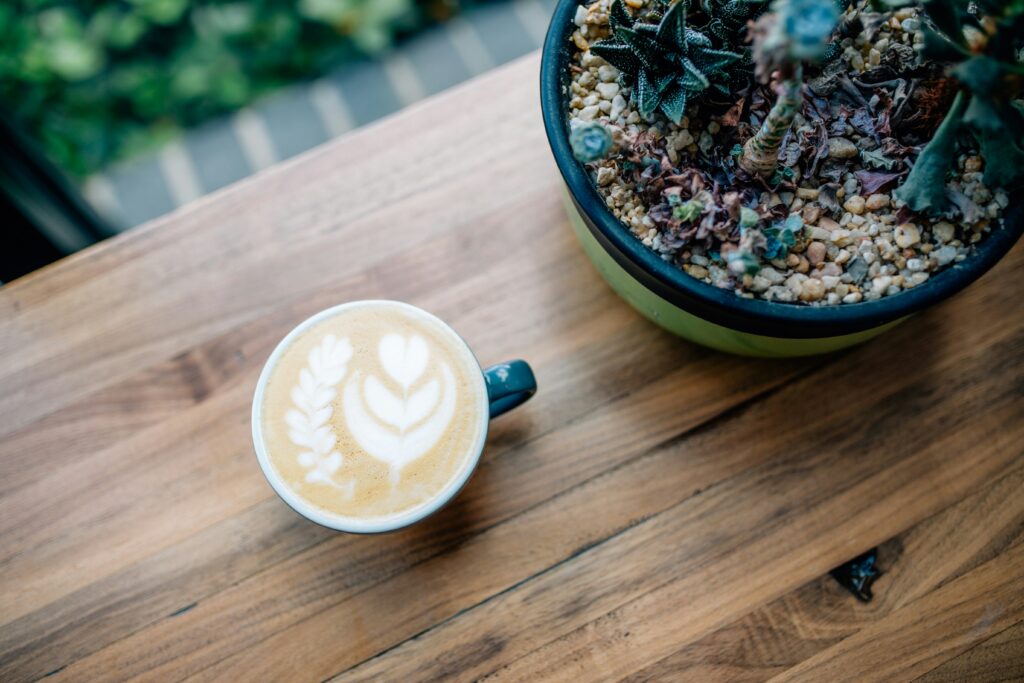 Tasse de café avec latte art accompagnée d'une plante succulente sur une table en bois