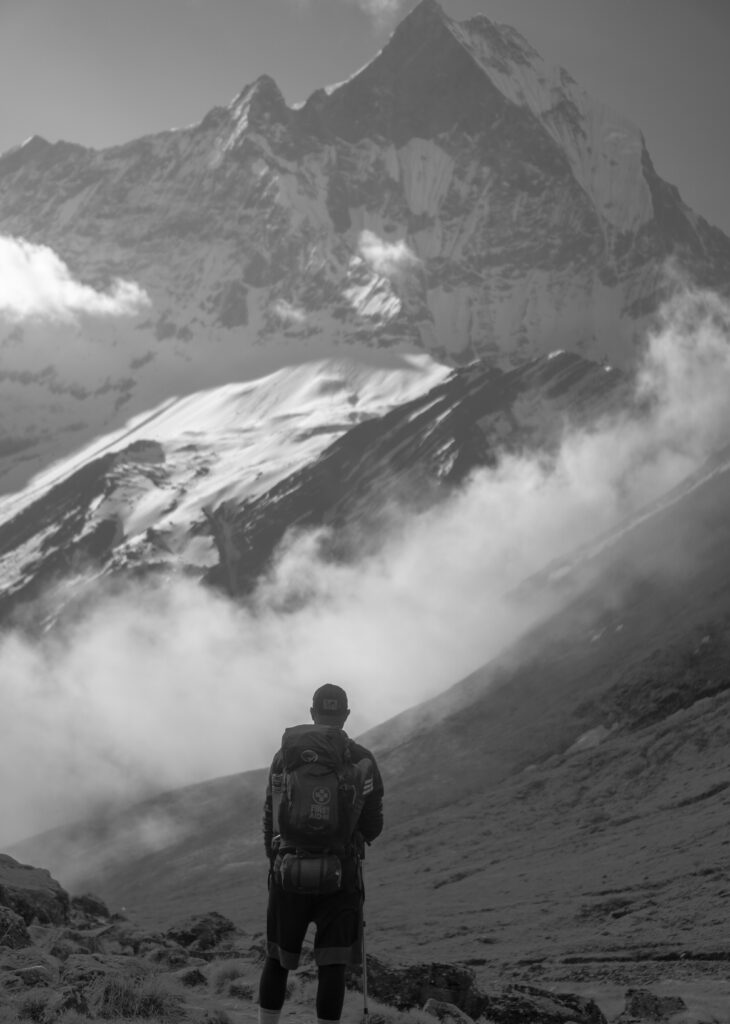 Trekkeur en solitaire face à une chaîne montagneuse imposante et brumeuse