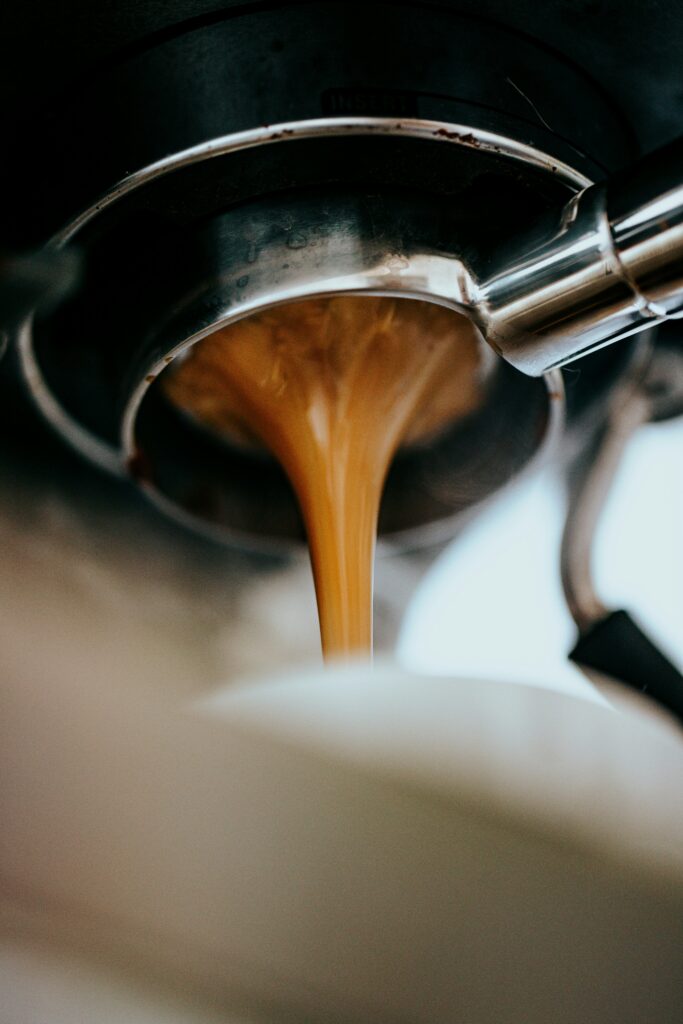 Extraction d'un espresso : le liquide doré s'écoule du porte-filtre en révélant la crema