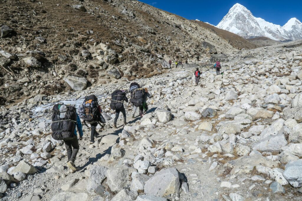 Porteurs himalayens transportant des charges lourdes sur un sentier de montagne escarpé
