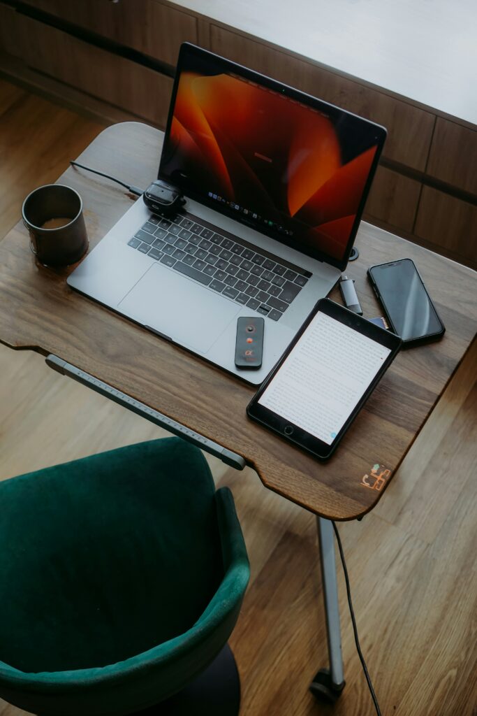 Espace de travail moderne avec plusieurs appareils connectés : laptop, tablette et smartphone sur un bureau en bois