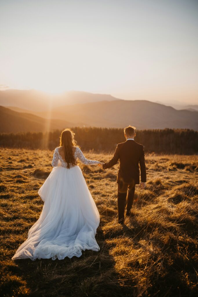 Couple marchant dans un champ au coucher de soleil, illustrant l'intimité et la sérénité capturées lors d'une séance engagement