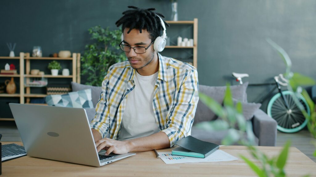 Utilisateur concentré portant des écouteurs lors d'une session de travail prolongée à domicile