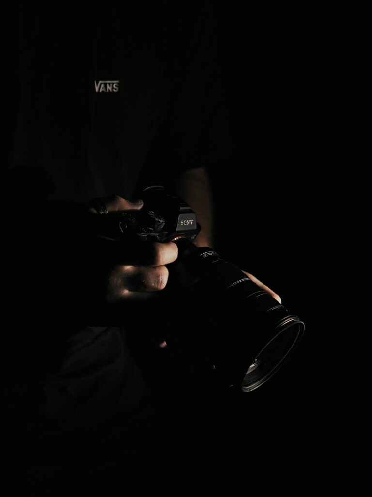 Mains de photographe tenant un appareil photo, illustrant la maîtrise technique et l'équipement professionnel