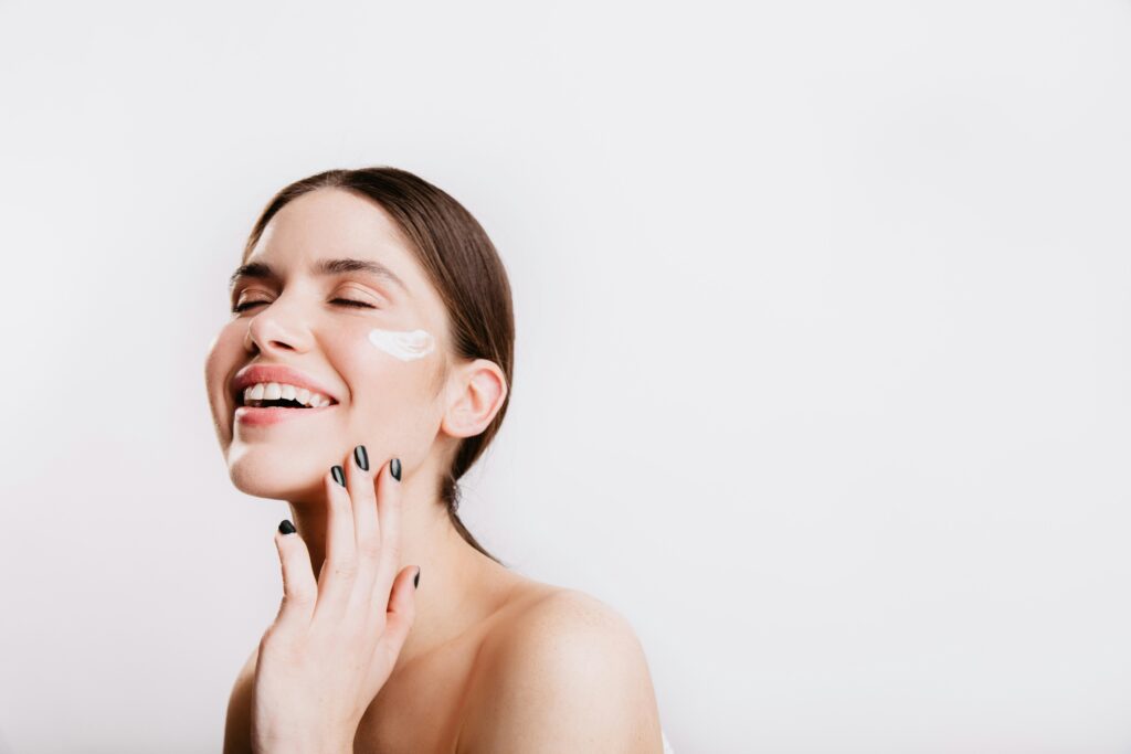 Femme satisfaite appliquant un soin visage Nūde, démontrant les résultats visibles de la routine